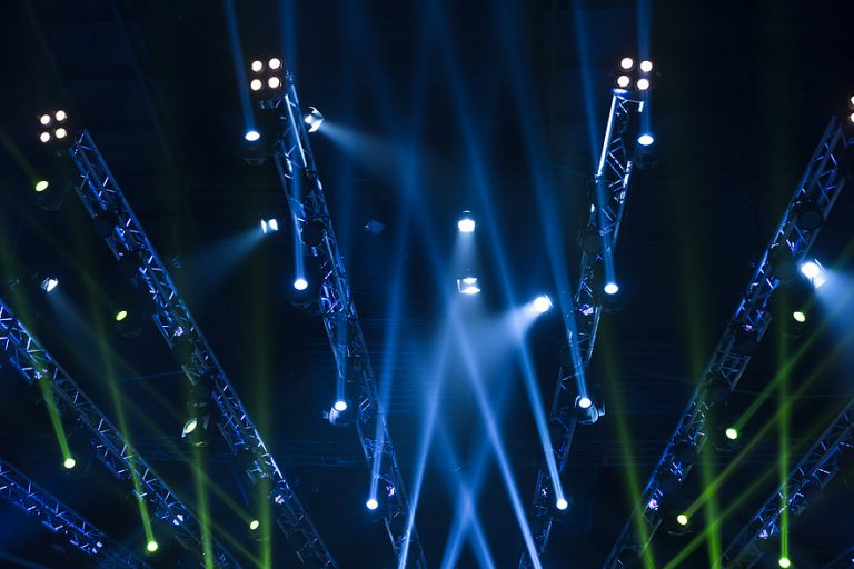 lighting setup featuring multiple beams of blue and green lights projected from metal trusses